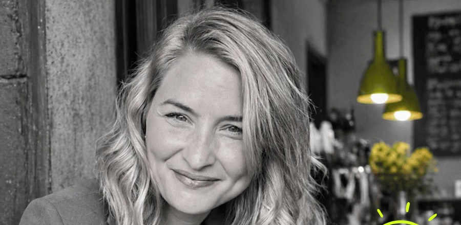 Mia, an ADHD founder, smiling in a cafe as she plans her week around her energy levels instead of the clock