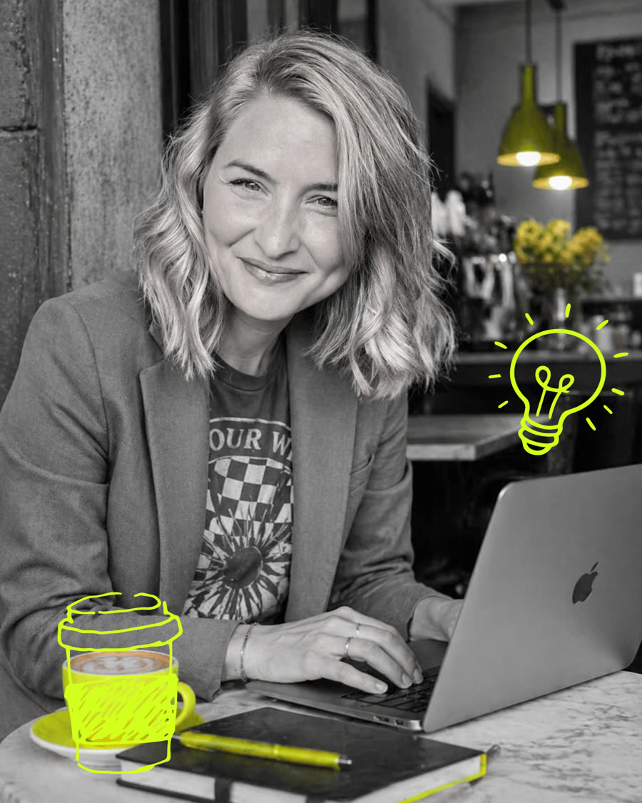 Mia working on her laptop in a cafe - greyscale photo with hand-drawn lime coffee cup and lightbulb doodles